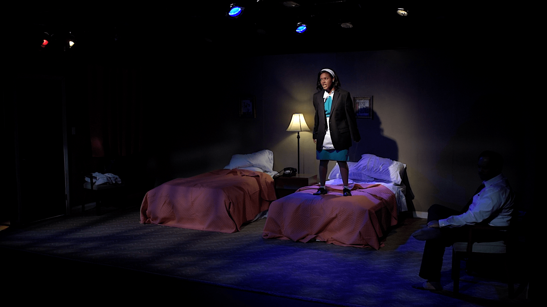 A woman is standing on a bed in a dark room.