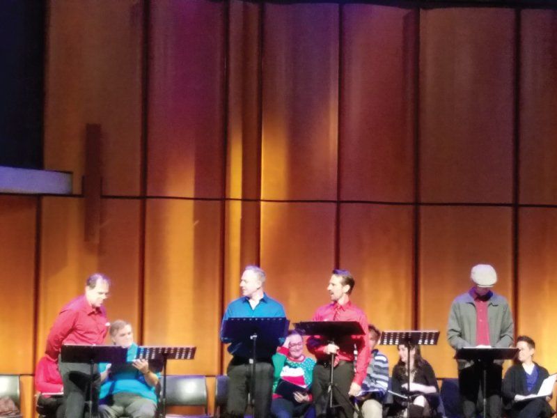 9 actors on stage at music stands or seated during reading.