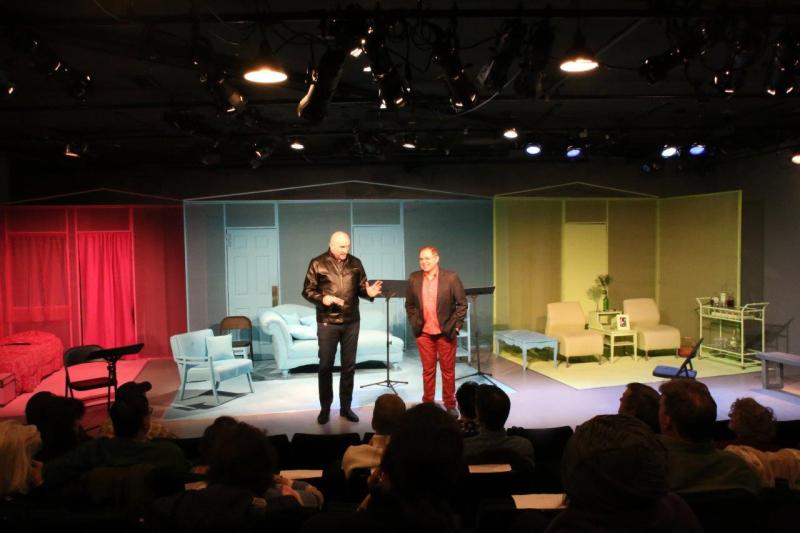 Man in leather jacket and man in brown suit jacket welcome audience at play reading.