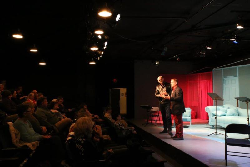Audience view of men welcoming audience at play reading.