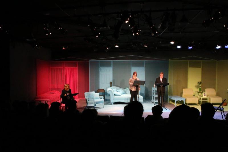 Woman seated with red background and woman and man standing in front of blue background.