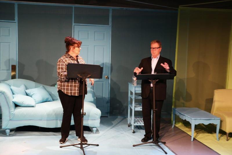 Woman in brown checked shirt talking with man in brown suit.