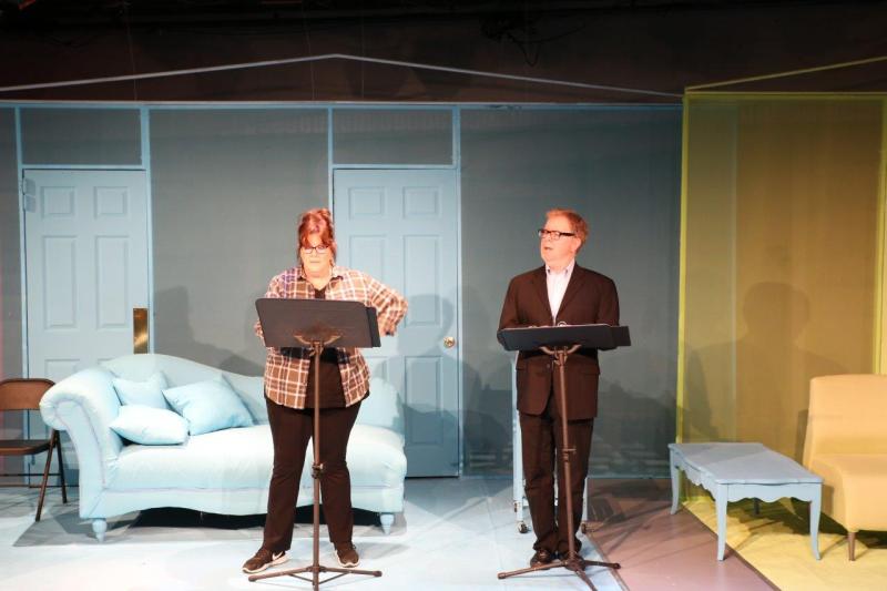 Woman in brown checked shirt and man in brown suit standing at music stands.