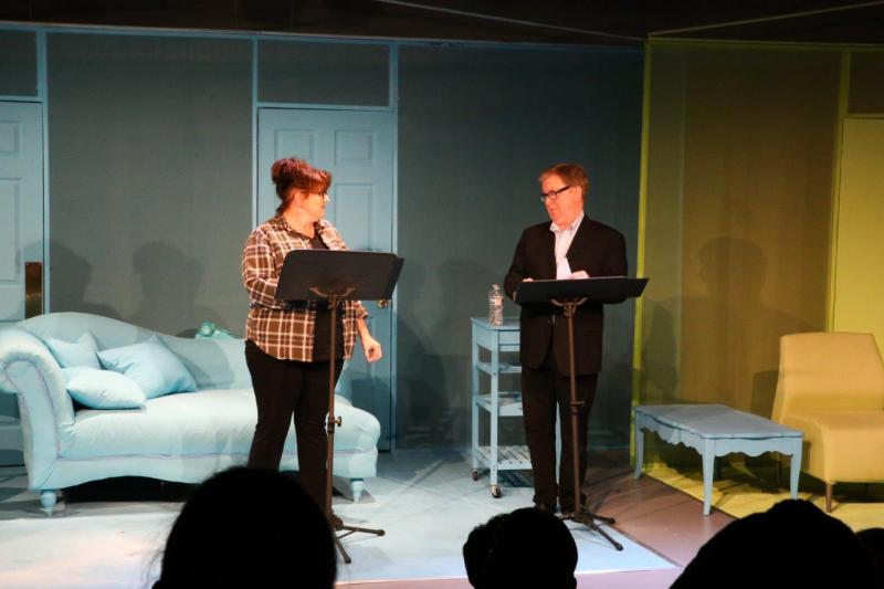 Woman in brown checked shirt and man in brown suit turned towards each other.