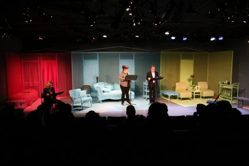 Audience view of woman seated on left and woman and man standing centerstage.