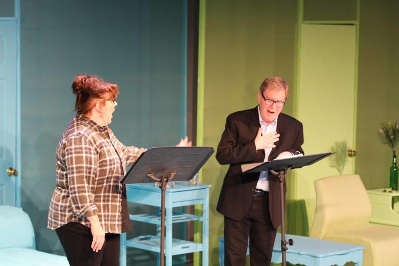 Woman in brown checked shirt looking amazed during conversation with man in brown suit.