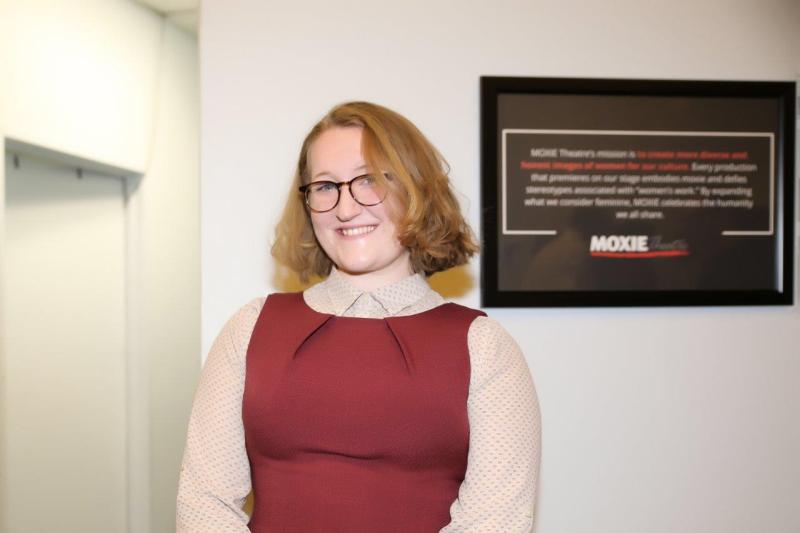House manager Siri, in red jumper, posing in theatre lobby after play reading.