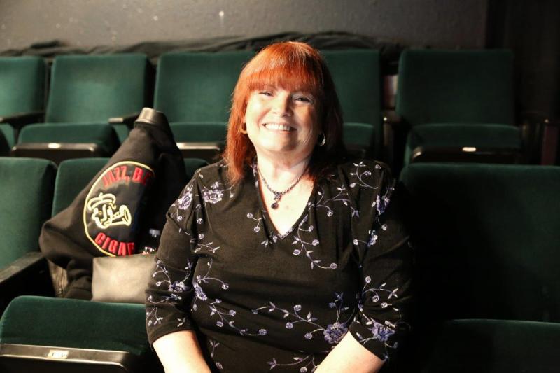 Attendee Barbara smiling for picture in theatre before the reading.