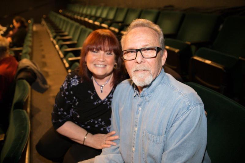 Howie and Barbara seated in theatre waiting for the reading to begin.