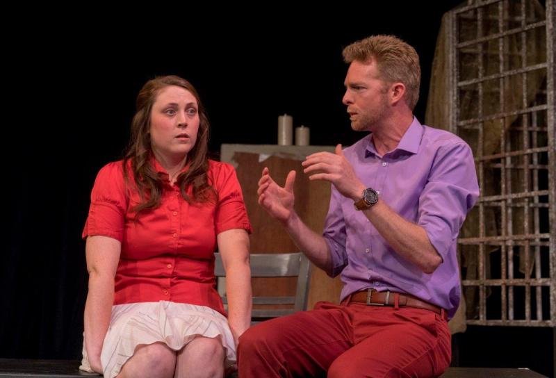 Woman in red blouse listening to man in lavender shirt  discussing a scene.
