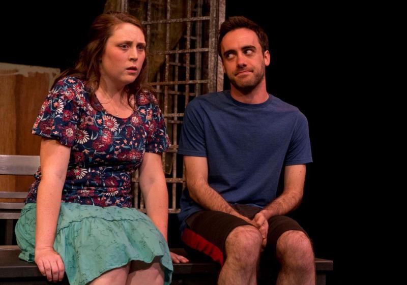 Woman in flowered blouse looks concerned while rehearsing with man in blue T-shirt.
