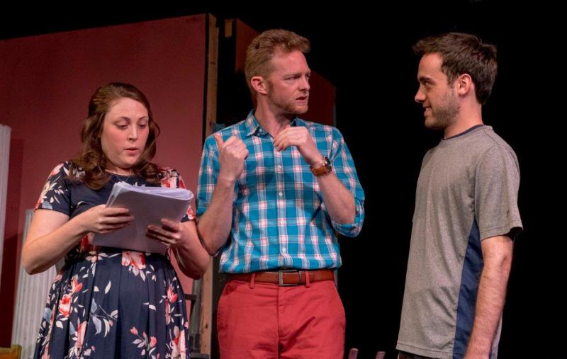Woman in flowered blouse with script, man in blue checked shirt, and man in grey shirt.