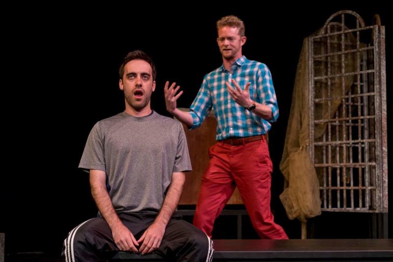 Seated man in grey shirt working on acting exercises with  standing man in blue checked shirt