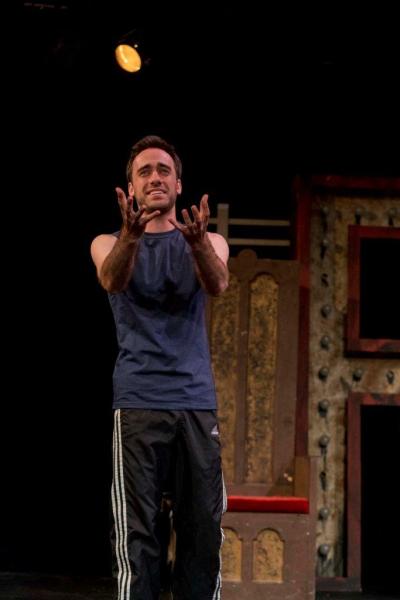 Man in blue t-shirt rehearsing a scene on stage.