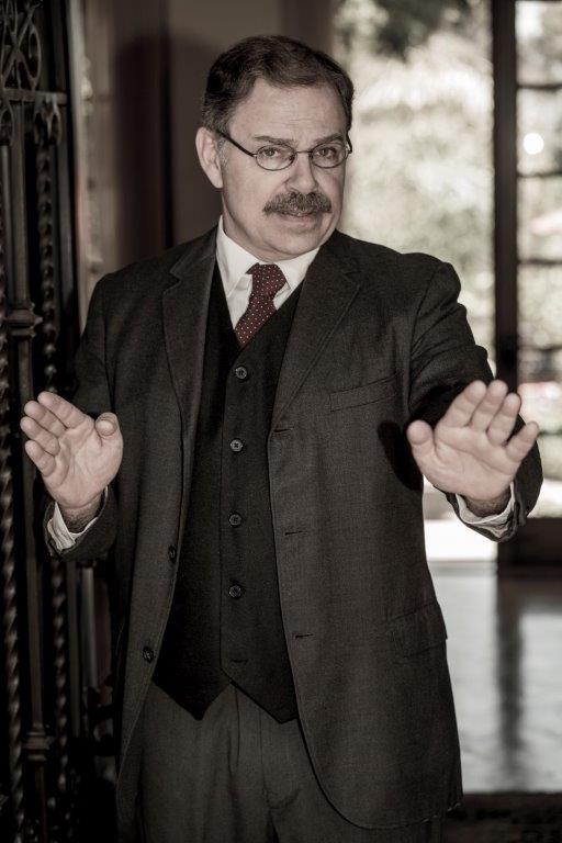 Actor Phil Johnson as President T. Roosevelt standing in open doorway, his hands in front of him.