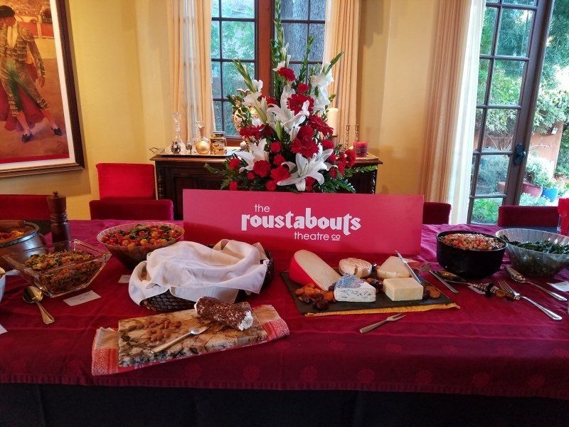 Dining room table with party food and theatre company sign