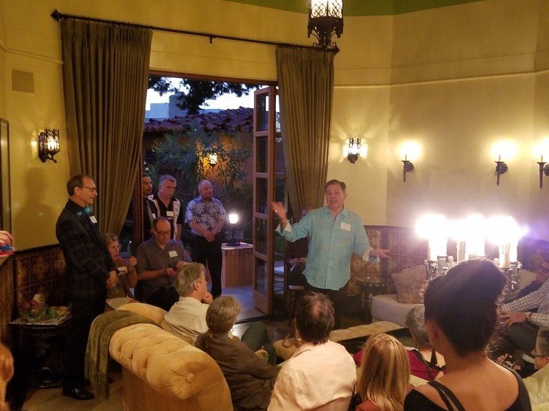 Guests in living room and patio listening to host Phil