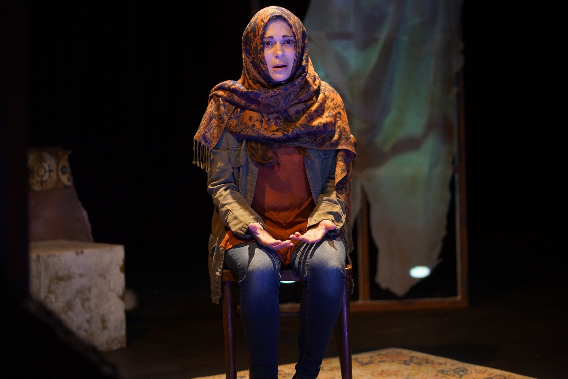 Young Mahshid looking worried as peers around a blue set piece.