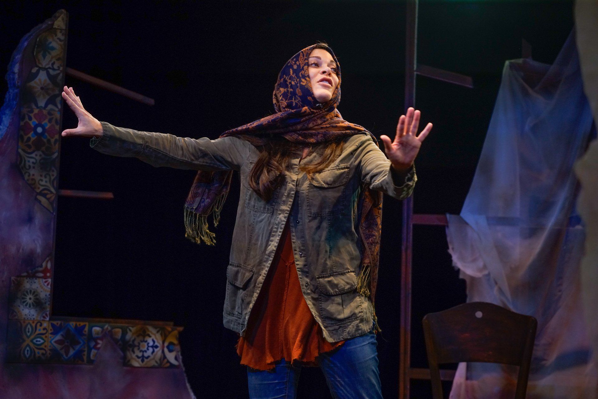 Young Mahshid dancing wearing headscarf, green jacket and orange sweater.