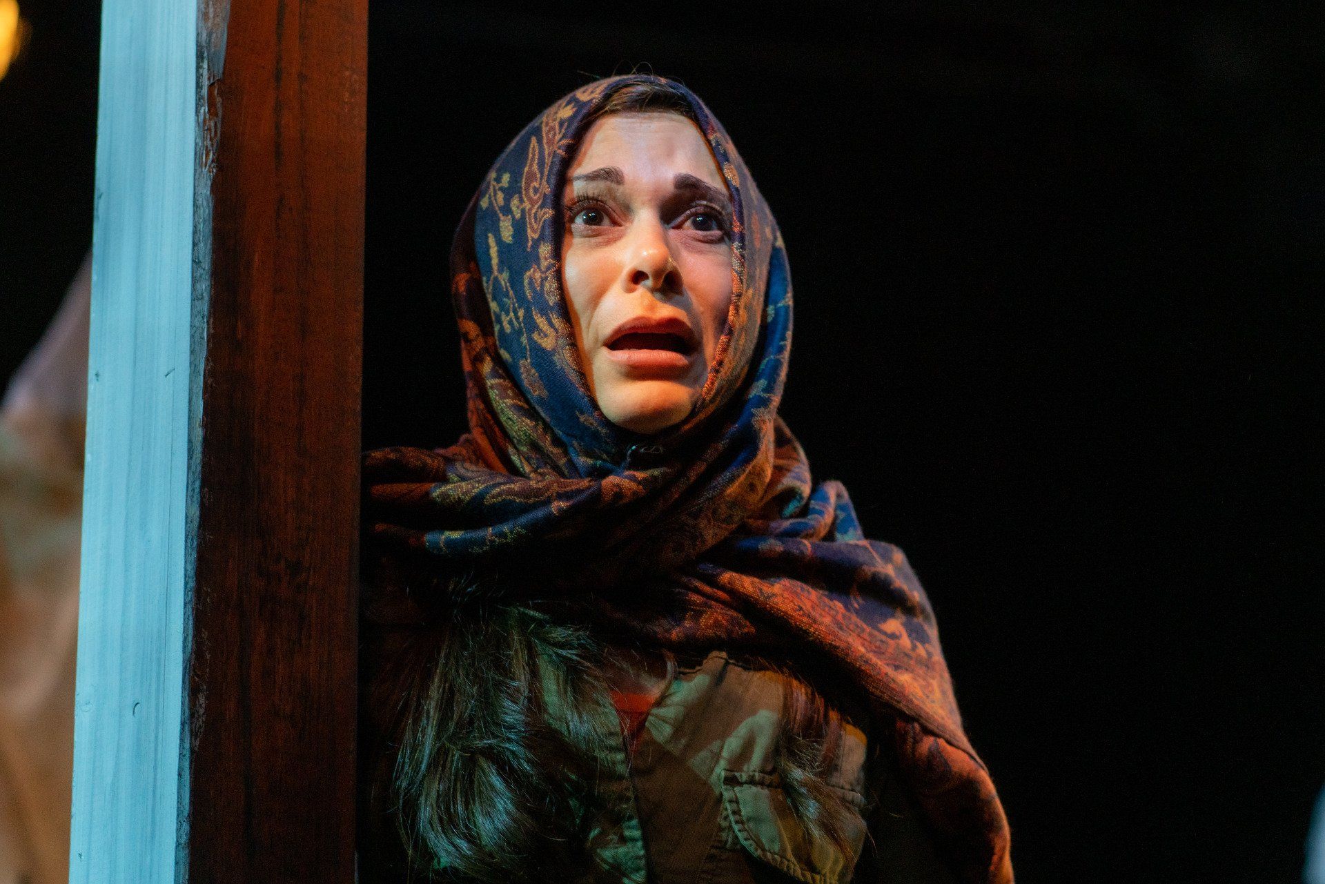 Young Mahshid wearing headscarf and green jacket  recalling a memory.