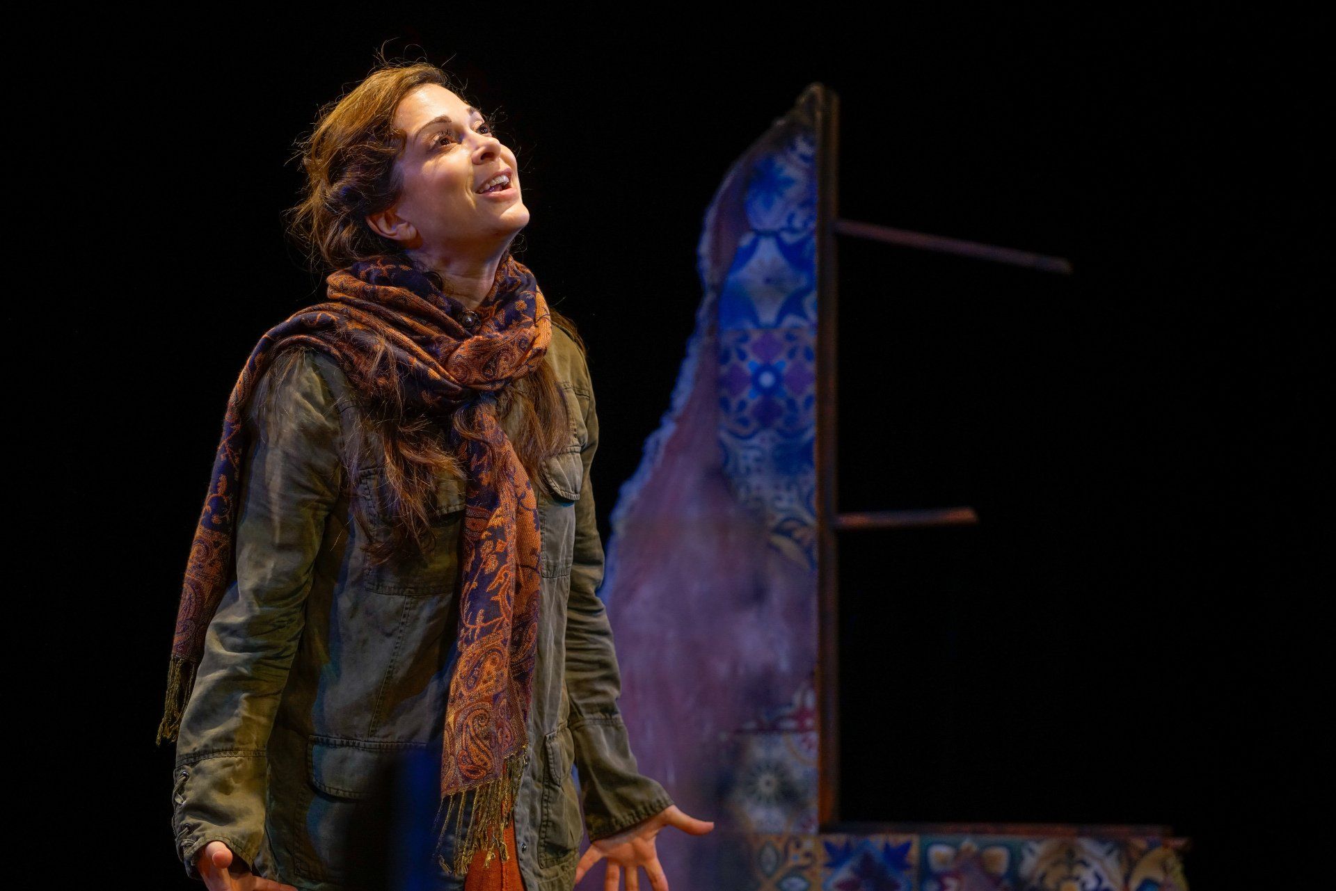 Young Mahshid wearing scarf and green jacket looking up.