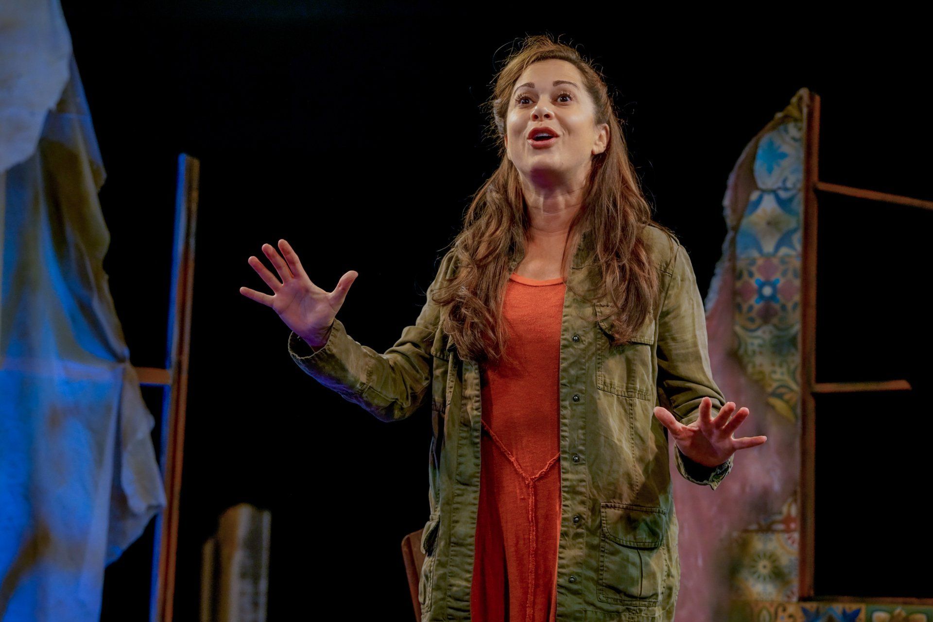 Young Mahshid wearing an orange sweater and green jacket and recalling a happy memory.