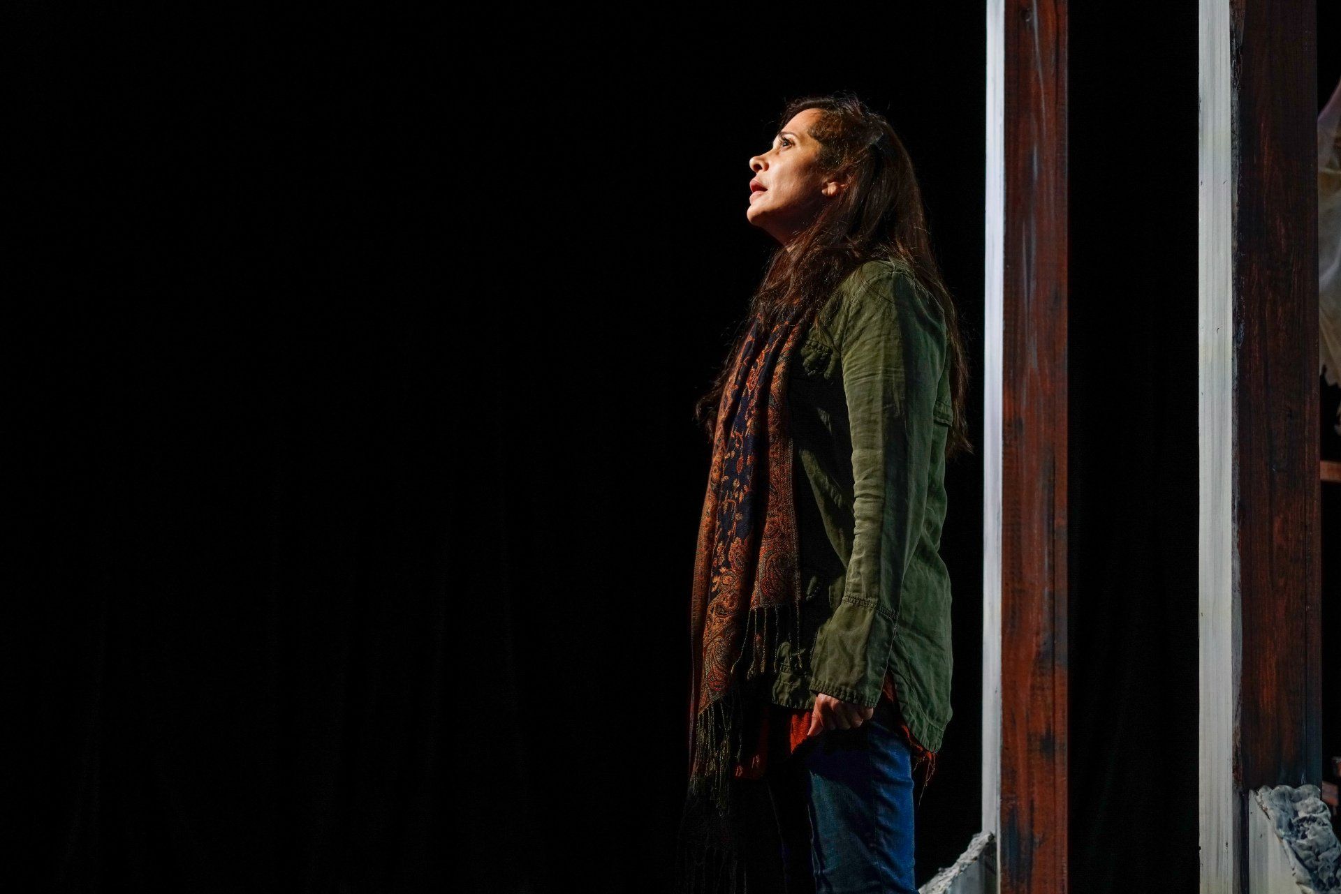 Young Mahshid standing against a wall considering her situation.