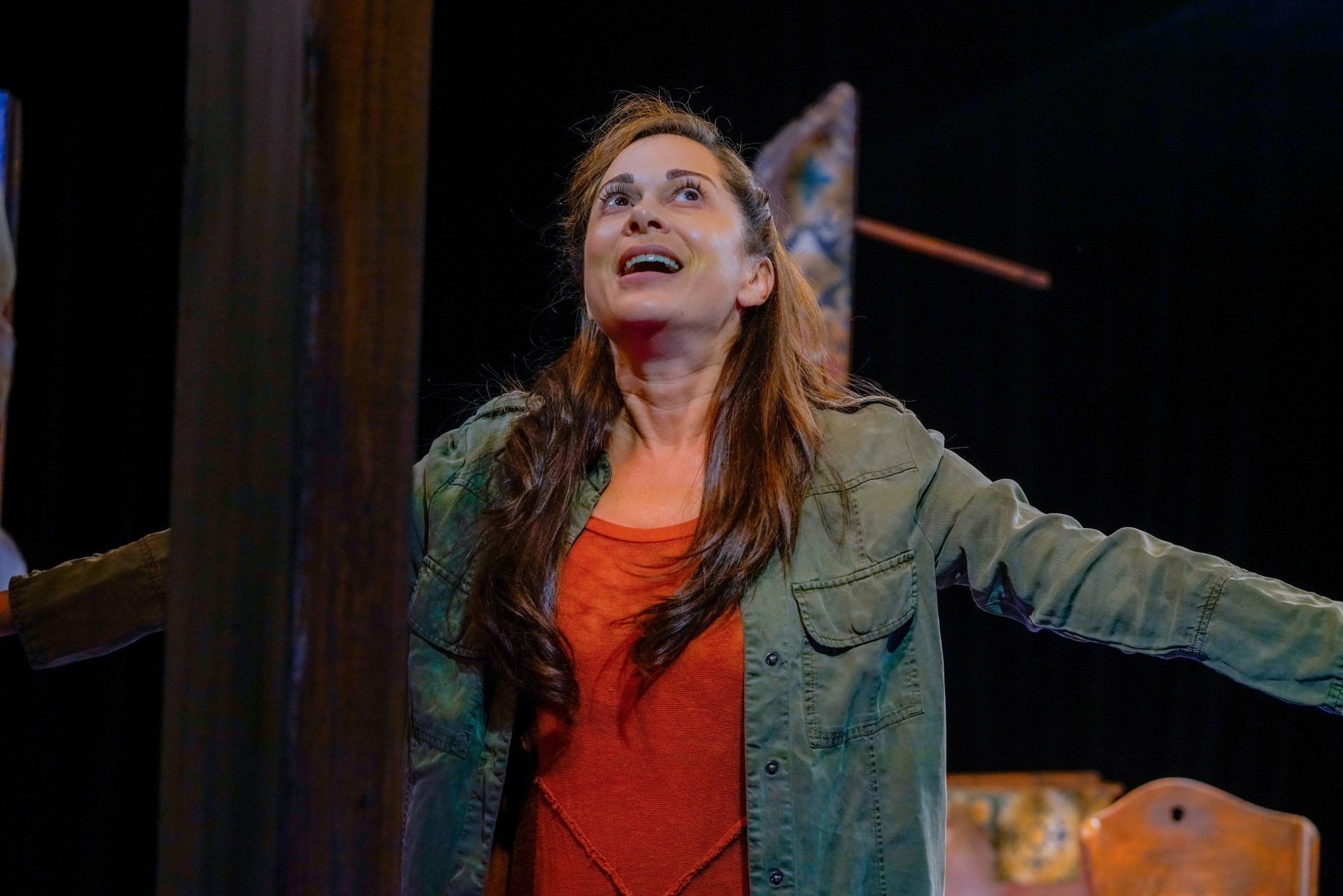 Young Mahshid wearing orange sweater and green jacket and thinking about a happy memory.