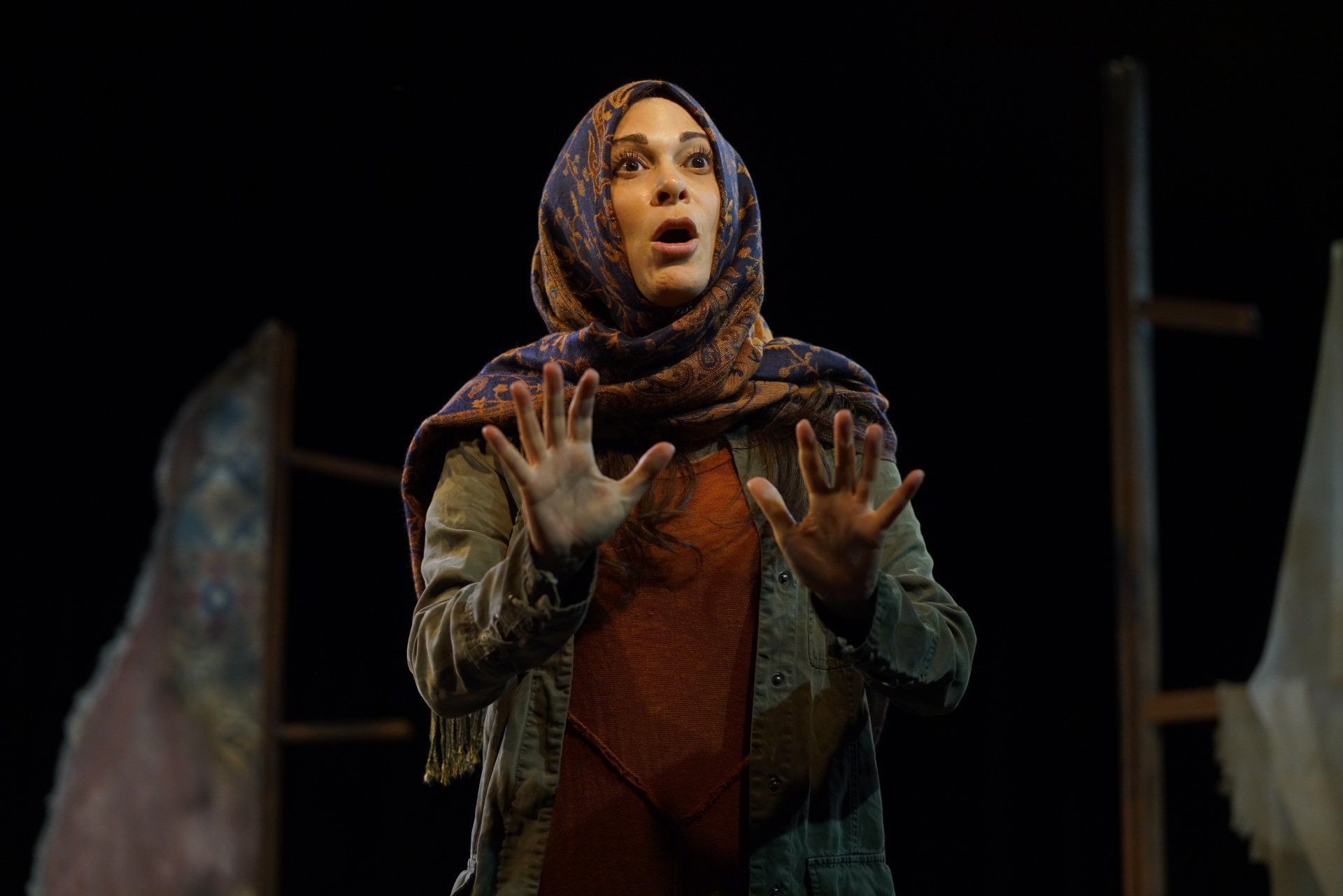 Young Mahshid seated wearing headscarf, green jacket, and orange sweater.