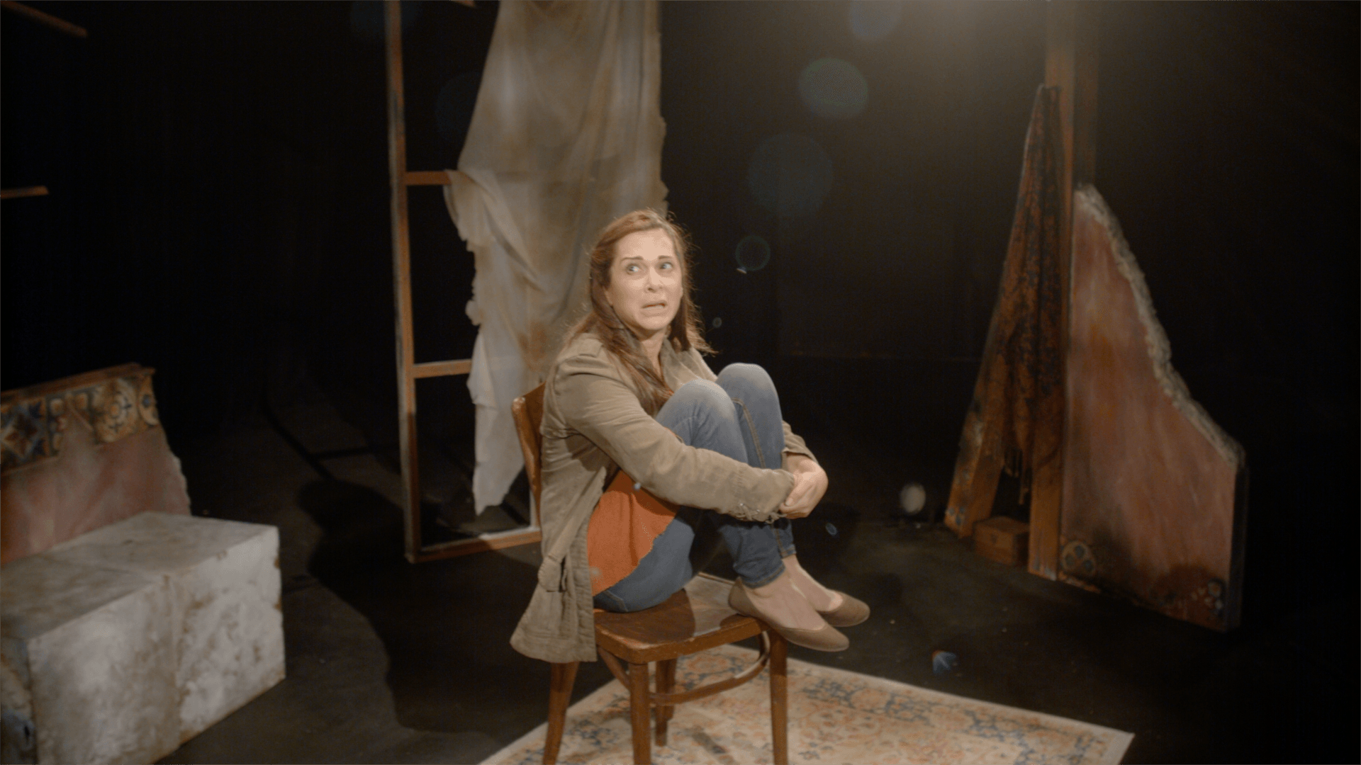 Young Mahshid seated on a chair and looking scared.