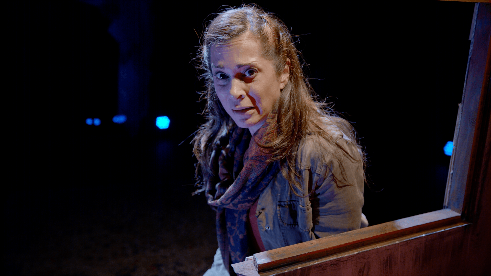 Young Mahshid wearing green jacket and scarf,  looking concerned.