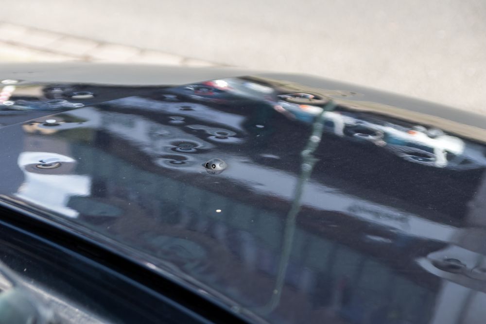 A Close Up Of A Black Car With Water Coming Out Of The Hood — Dynamic Dentz Smash Repair in South Nowra, NSW