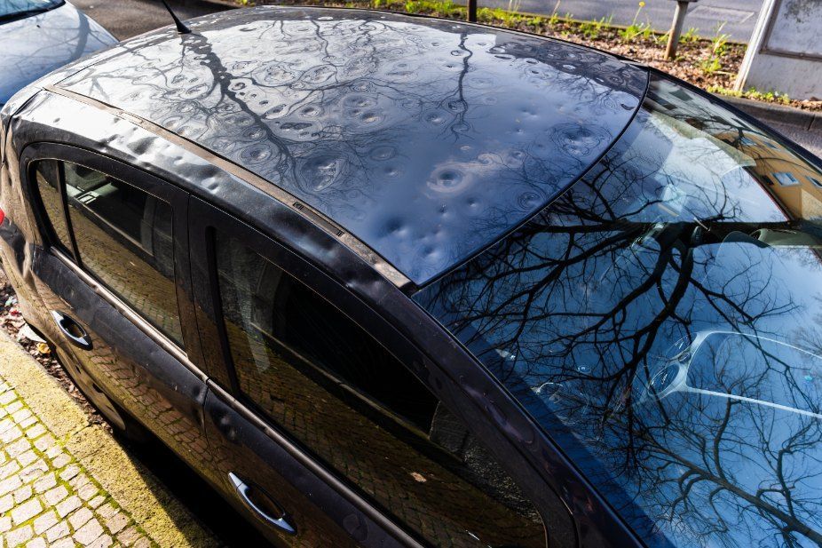 A Black Car With a Hail Damaged Roof is Parked on the Side of the Road — Dynamic Dentz Smash Repair in South Nowra, NSW