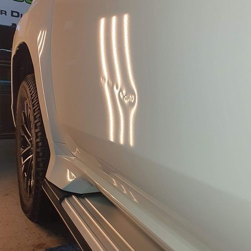 Close up of a white car with dents on the door — Dynamic Dentz Smash Repair in South Nowra, NSW
