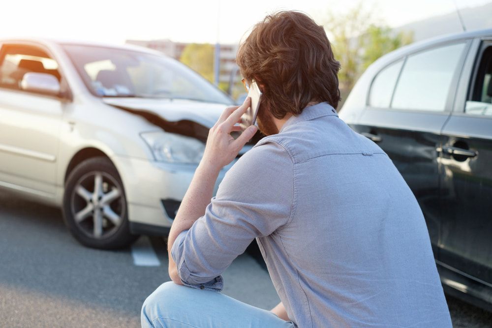 A Man is Talking on a Cell Phone in Front of a Car Accident — Dynamic Dentz Smash Repair in South Nowra, NSW