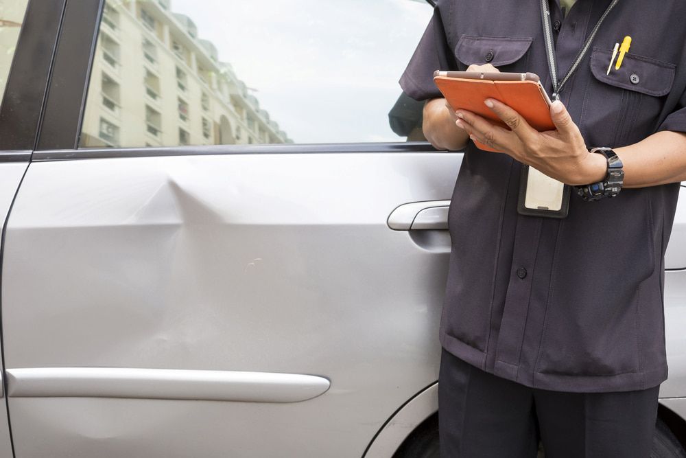 A Man is Standing Next to a Car Holding a Clipboard — Dynamic Dentz Smash Repair in South Nowra, NSW