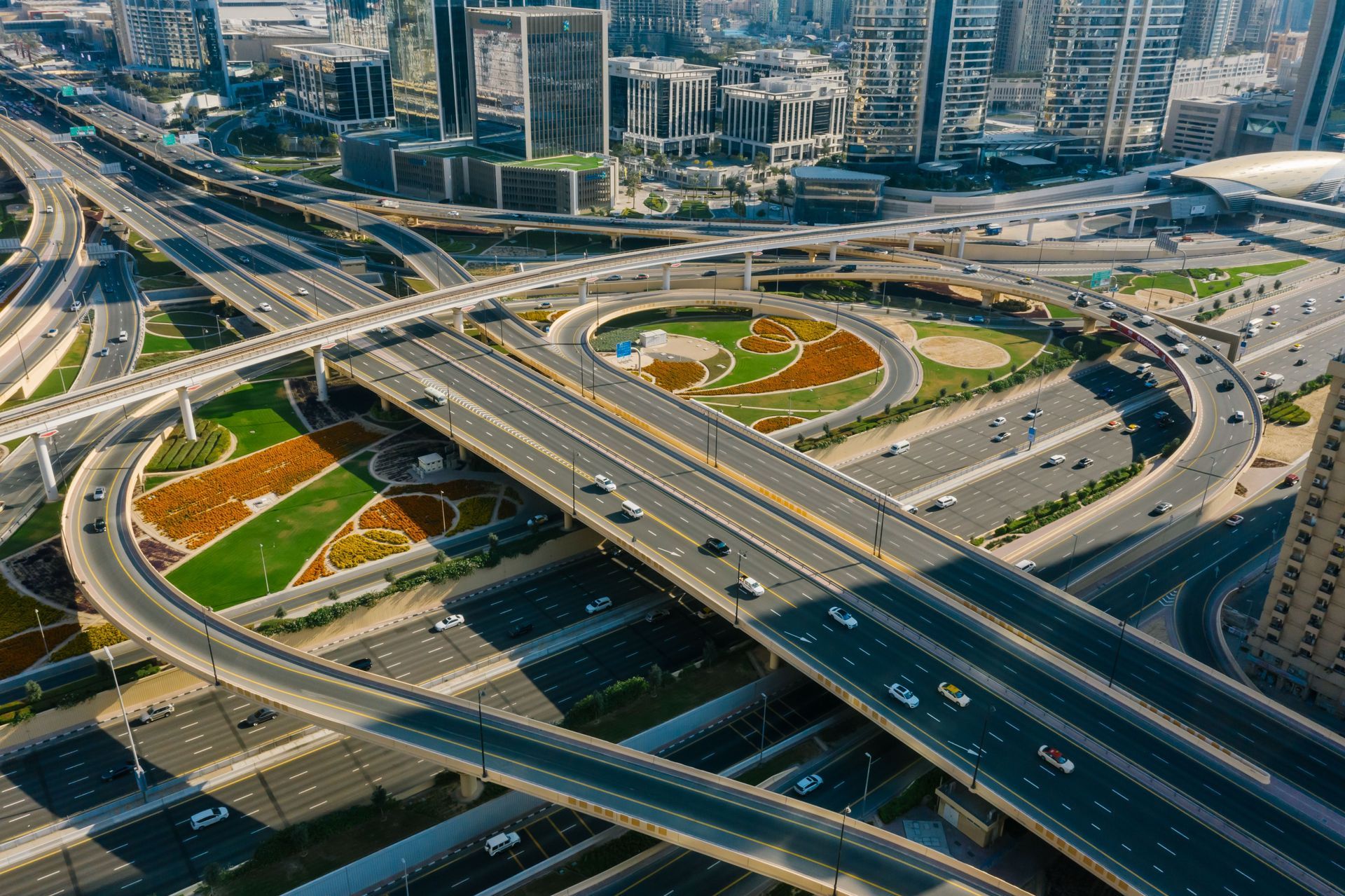 Aerial view of a multi-level highway interchange with cars and landscaped green medians in a city.