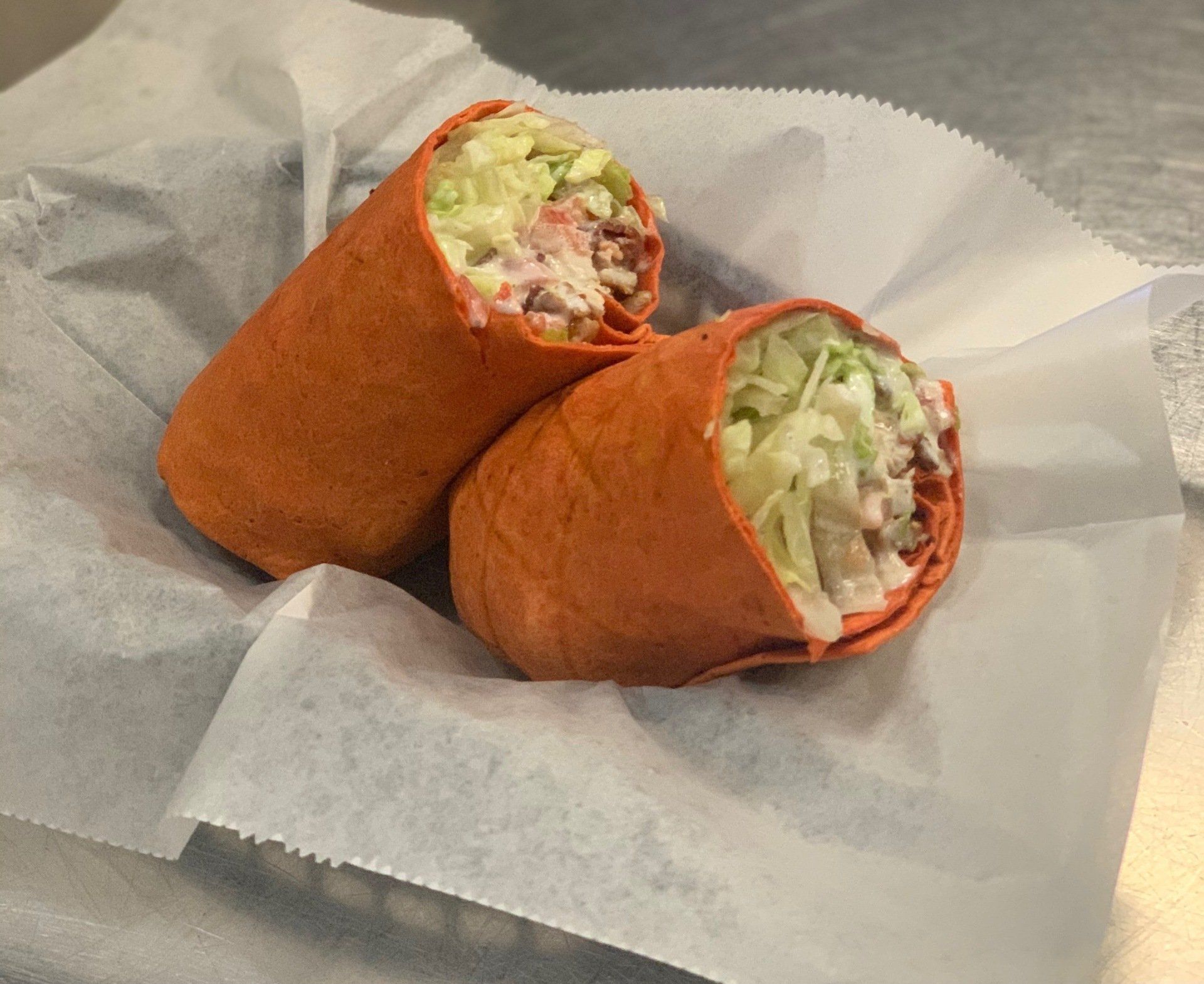 Two wraps are sitting on a piece of paper on a table.