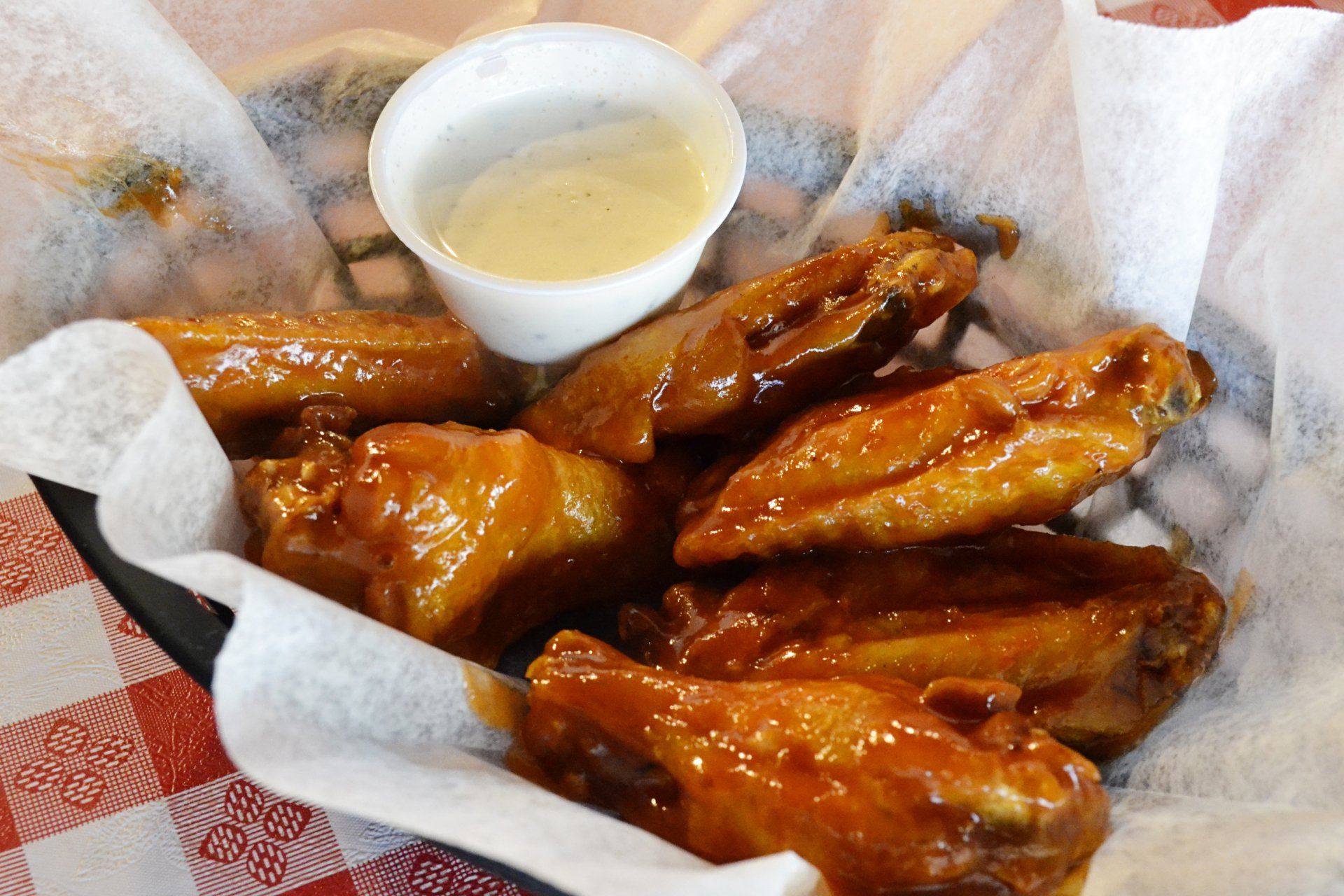 A basket of chicken wings with a dipping sauce