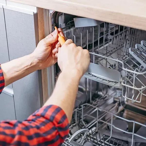 Person Repairs Dishwasher With a Screwdriver, Open Door, Red Plaid Shirt — SealTite in Terranora, NSW