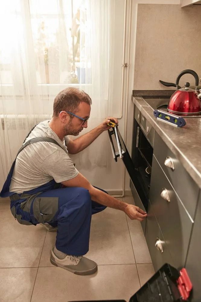 Man Crouched, Opening Oven Door in Kitchen, Wearing Overalls — SealTite in Lismore, NSW