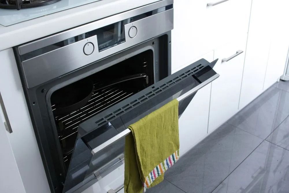 Opened Oven in a White Kitchen With a Green Towel Hanging From the Door — SealTite in Terranora, NSW
