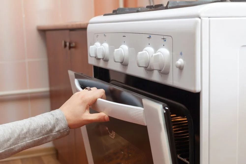 Hand Opening a White Oven Door in a Kitchen — SealTite in Ballina, NSW
