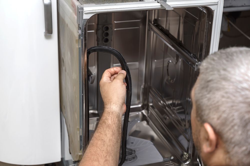 Person Installing a Black Rubber Seal on the Inside of a Dishwasher Door — SealTite in Kingscliff, NSW