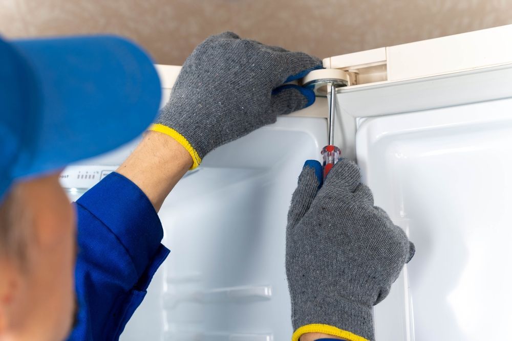 Person in Gray Gloves Using a Screwdriver on a White Refrigerator Door, Likely Repairing It — SealTite in Lismore, NSW