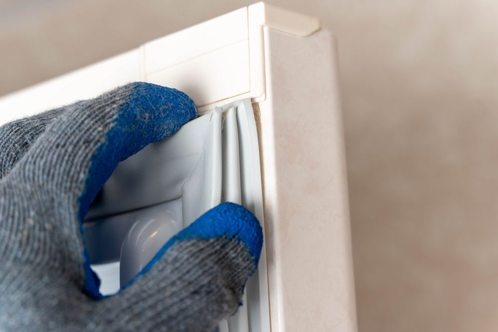 A Gloved Hand Installing a Gray Rubber Seal on a White Door Frame — SealTite in Gold Coast, QLD