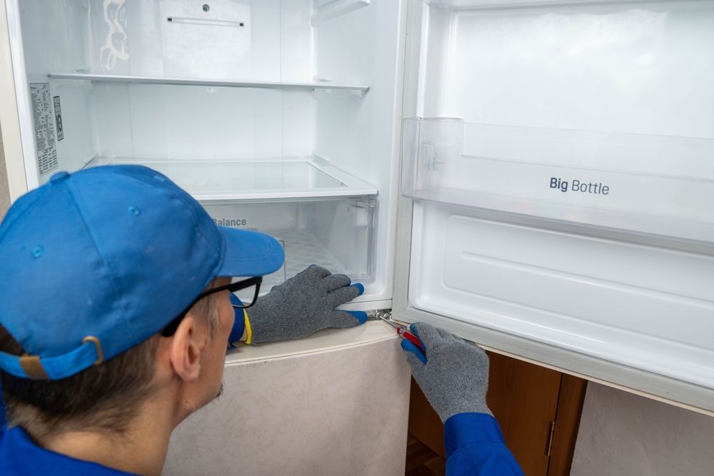 Person in Blue Cap and Gloves Repairing a Refrigerator — SealTite in Gold Coast, QLD