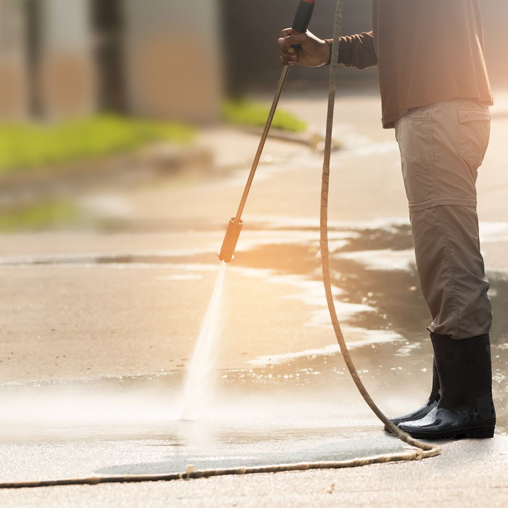 A man is using a shovel to spread gravel on a patio.
