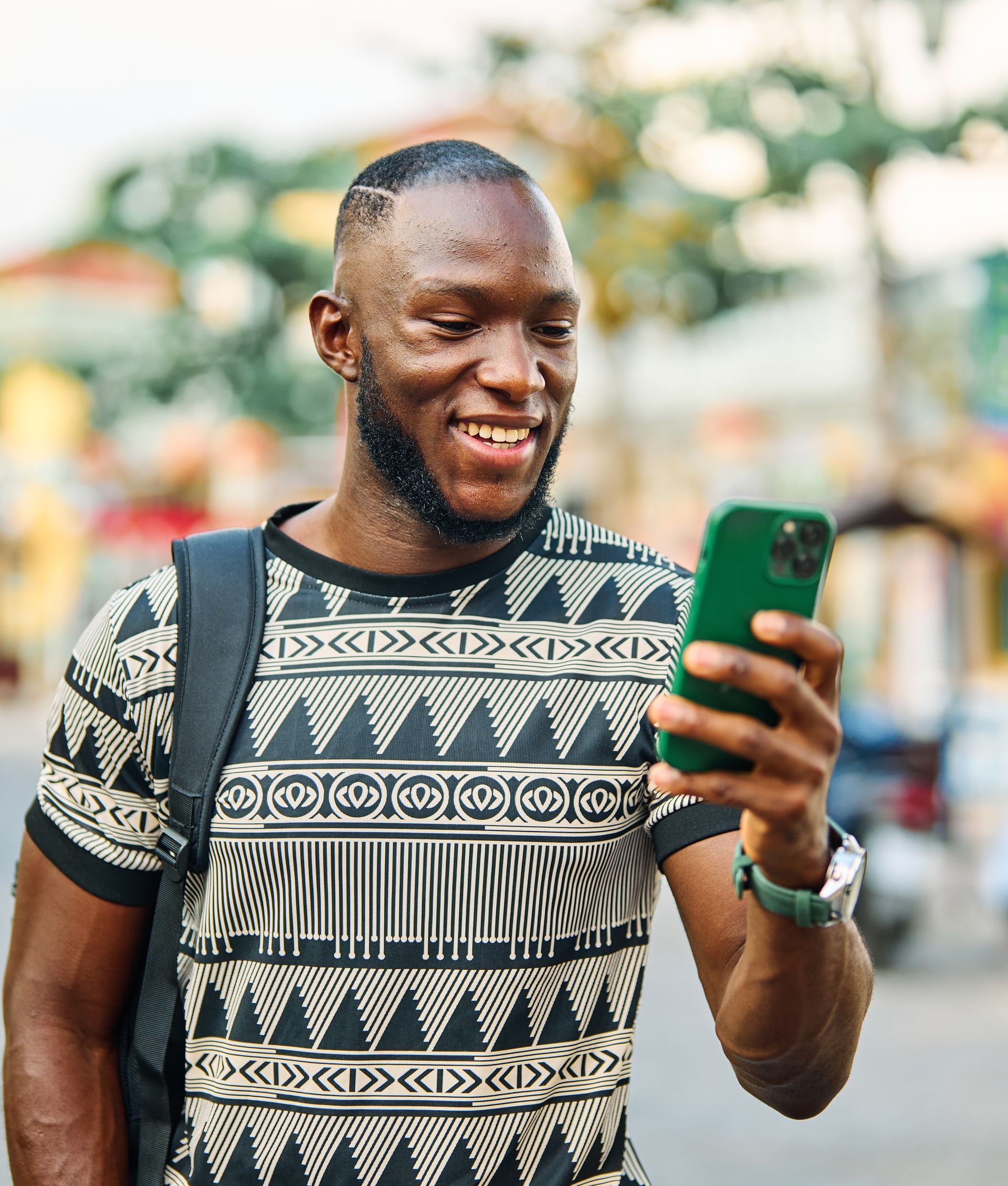 A man is smiling while looking at his cell phone.