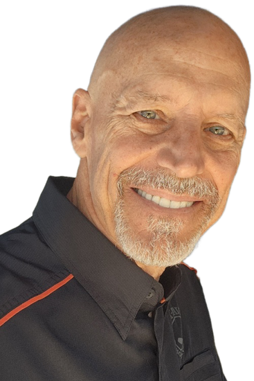 Smiling bald man with gray stubble beard in a black shirt with orange trim, looking at the camera.